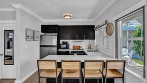 Een moderne keuken met een centraal eiland, zwarte kasten, roestvrijstalen apparatuur en een groot raam met uitzicht.