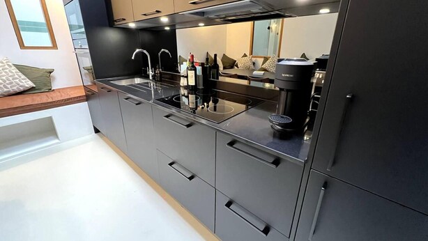 Een moderne keuken met grijze kastjes, een zwart aanrecht en een ingebouwde espressomachine.