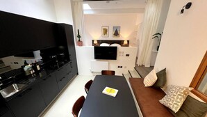 Een ruimtelijk ingerichte leefruimte met kitchenette, eethoek en zithoek.