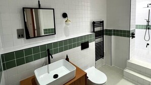 Een moderne badkamer met een wit wastafelmeubel, een spiegel, een toilet en een douchehoek.