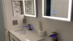 A modern bathroom with two sinks, a mirror, and a toilet paper holder. - Hollywood Island (Indianapolis)