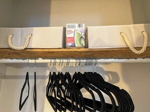 Une étagère avec un sac blanc, un fer à repasser compact à vapeur Black+Decker Easy Steam et un Black+Decker Smooth Glider.