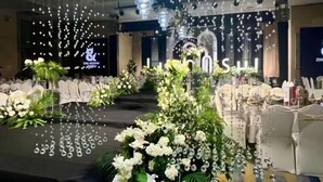 A banquet hall with a stage, white floral arrangements, and hanging crystal decorations. - Canal Hotel (Jiaxing)