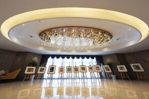 A lobby with a circular ceiling design, artwork on easels, and a reflective floor. - Canal Hotel (Jiaxing)