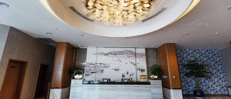Un vestíbulo de hotel con una recepción, una gran araña y un diseño de interiores moderno.
