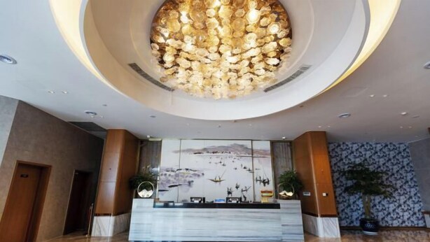 A modern lobby with a circular chandelier, a reception desk, and a large wall mural. - Canal Hotel (Jiaxing)