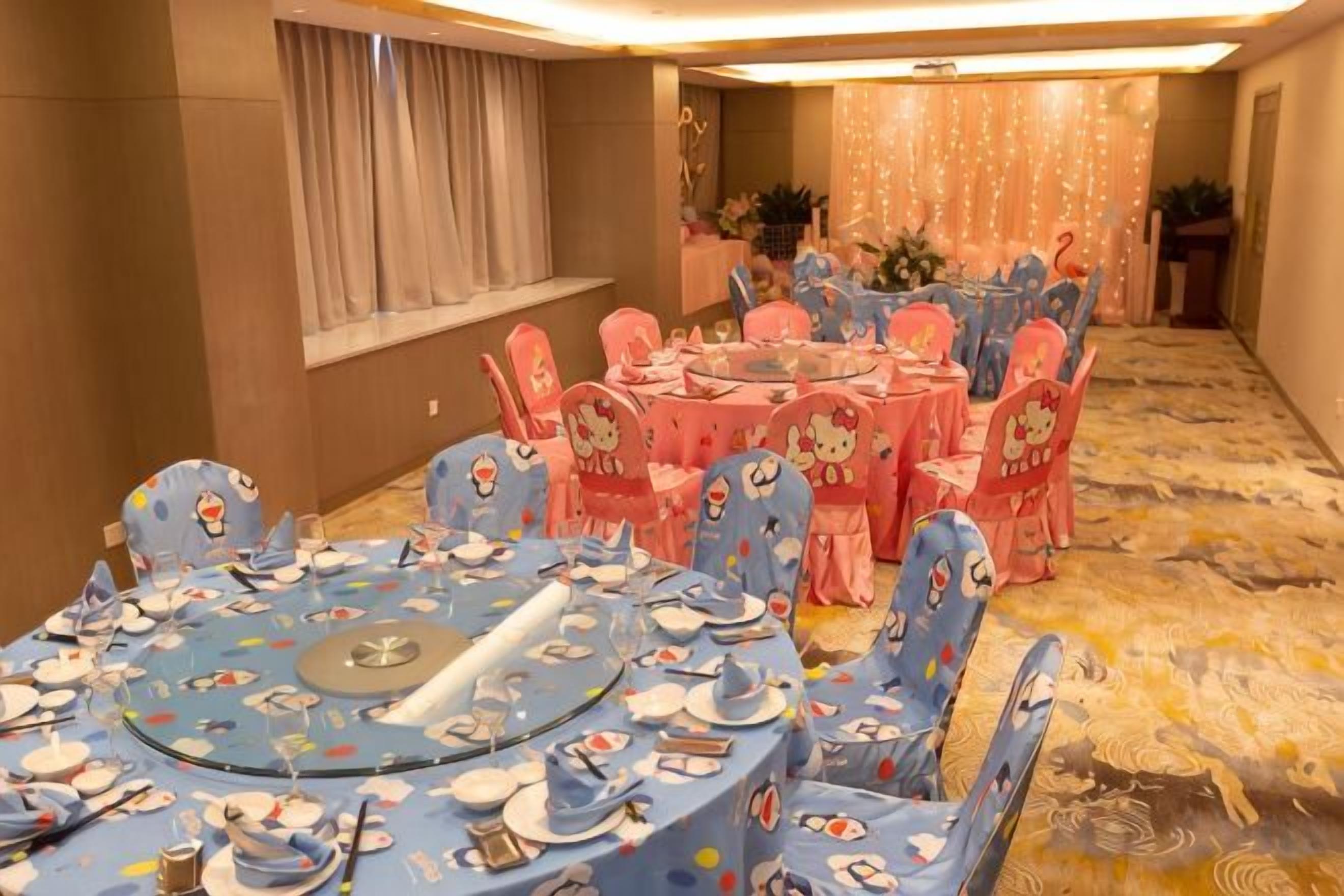 A banquet hall with round tables and chairs, a carpeted floor, and a window with curtains.