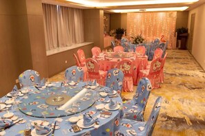 A banquet hall with round tables and chairs, a carpeted floor, and a window with curtains. - Canal Hotel (Jiaxing)
