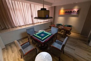 Una habitación con mesa de billar, asientos cómodos, ventana con cortinas y un cuadro en la pared.