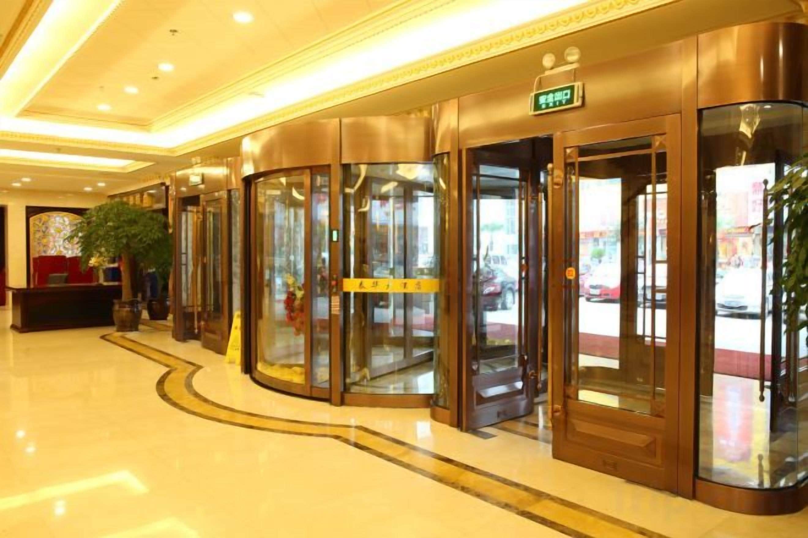 Un hall de hotel con puertas giratorias, un mostrador de recepción y una planta en maceta.
