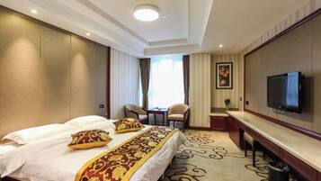 A hotel room with a bed, a desk, a television, and a window with curtains.
