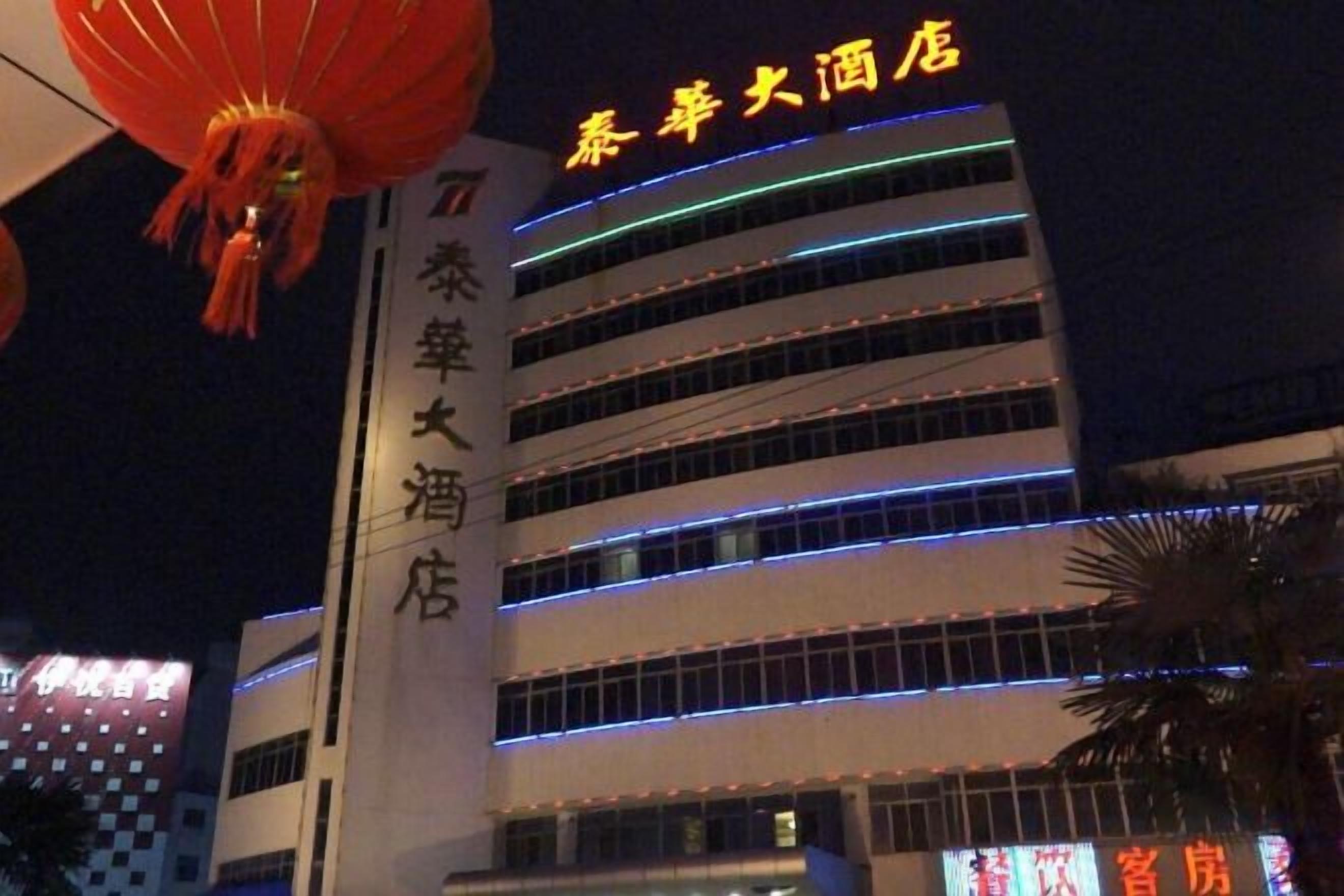 A multi-story hotel with illuminated signage and a vertical sign indicating a specific hotel name.