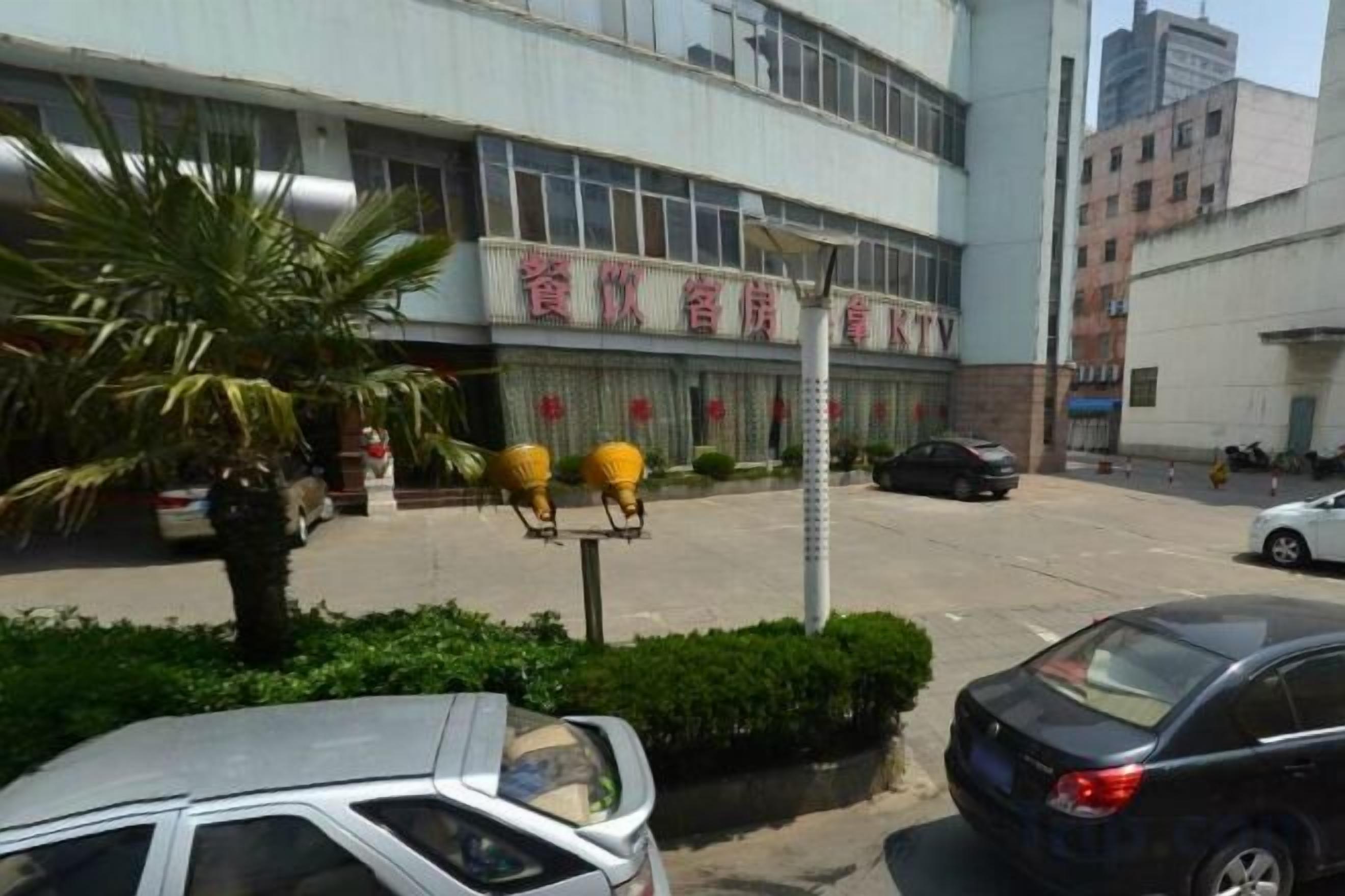 A building with a sign that reads 'Hotel' and a parking lot with cars.