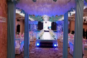 Un espacio para eventos decorado con un escenario, mesas y sillas.