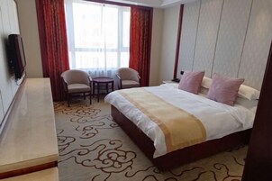 Una habitación de hotel con una cama, dos sillas, una mesita y un televisor.