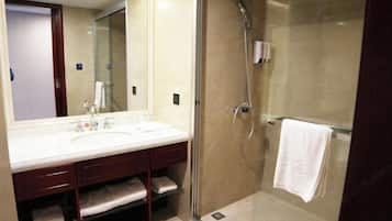 Een badkamer met een douchecabine, een wastafel met spiegel en een handdoekrek.