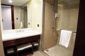 Un baño con cabina de ducha de vidrio, lavamanos con espejo y un perchero para toallas.