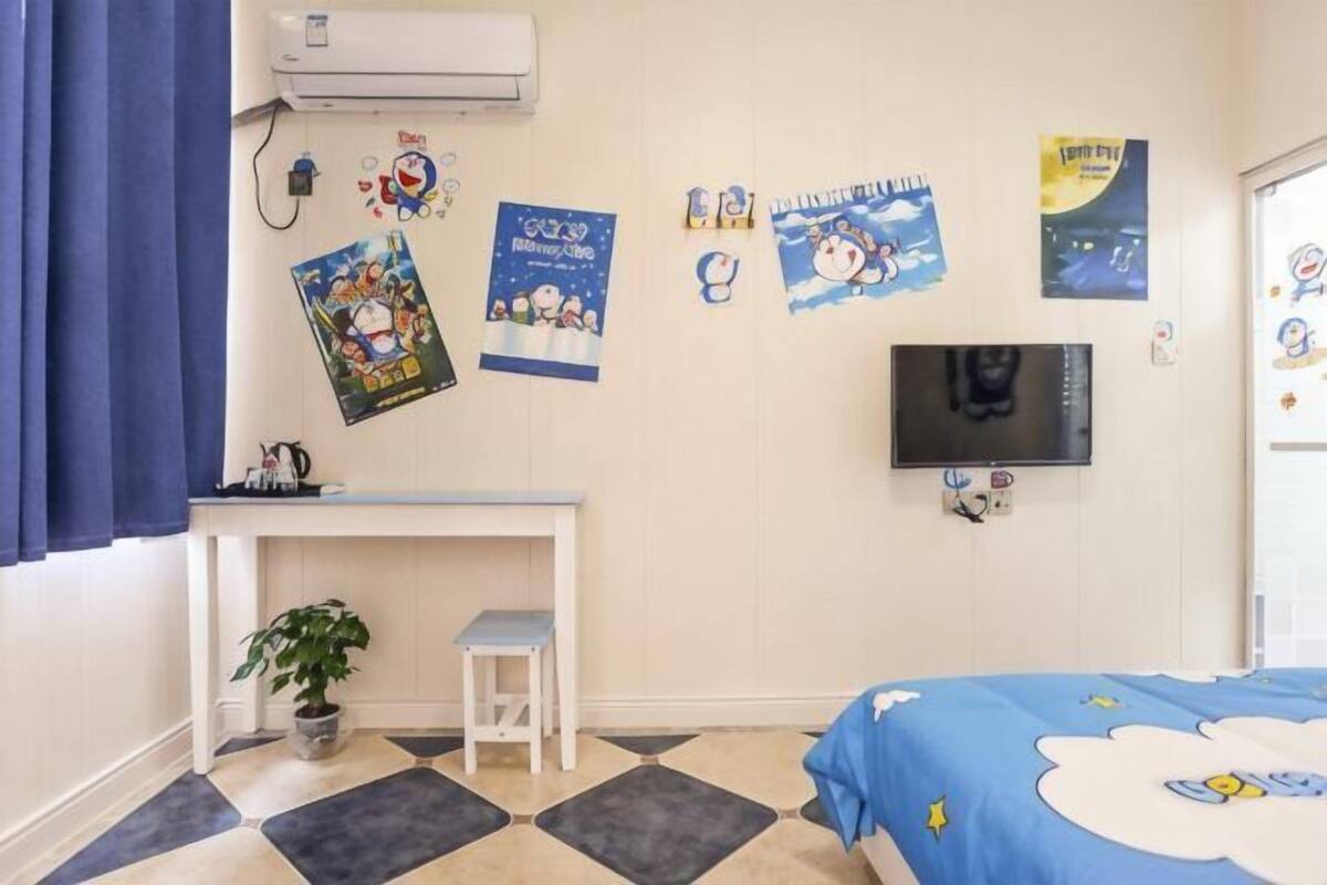 A room with a bed, a desk, a TV, and wall decorations.
