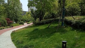 A pathway curving through a lush green park with a paved walkway and a small black lamp post.