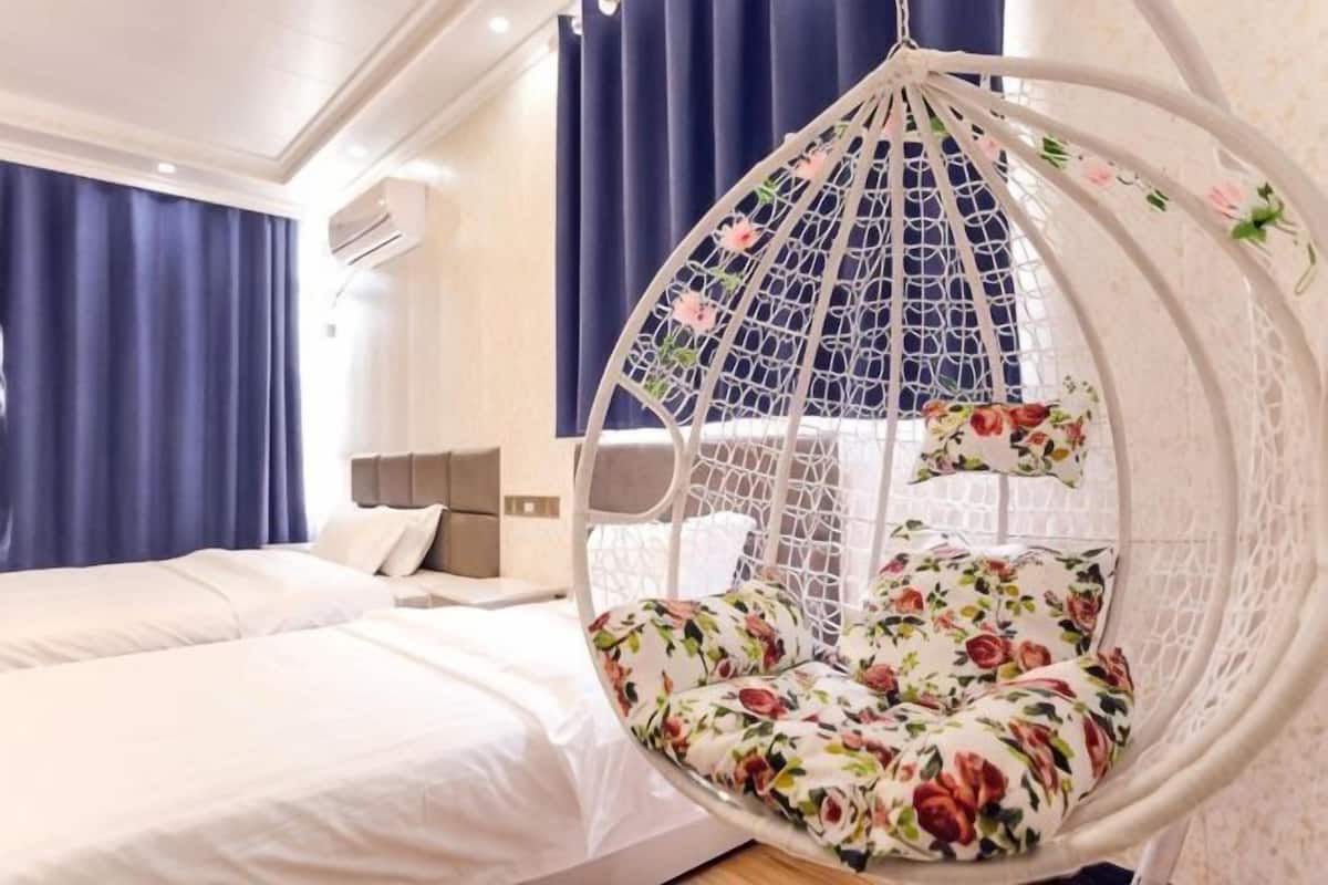 A room with a bed, a hanging chair, and a bedside table.