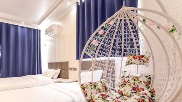 A bedroom with a hanging chair, a bed, and a nightstand.