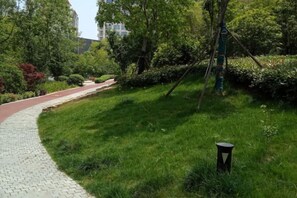 A paved pathway curving through a grassy area with trees and a lamp post. - Nanjing Lafei Hotel Lukou Airport Branch (Nanjing)