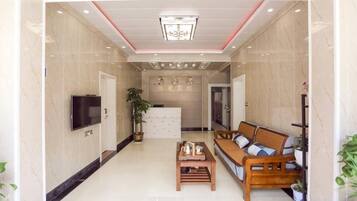 Vestíbulo de hotel con mostrador de recepción, zona de estar y televisión.