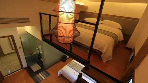 Une chambre à coucher avec un lit, une lampe suspendue, un escalier en bois et une petite table.