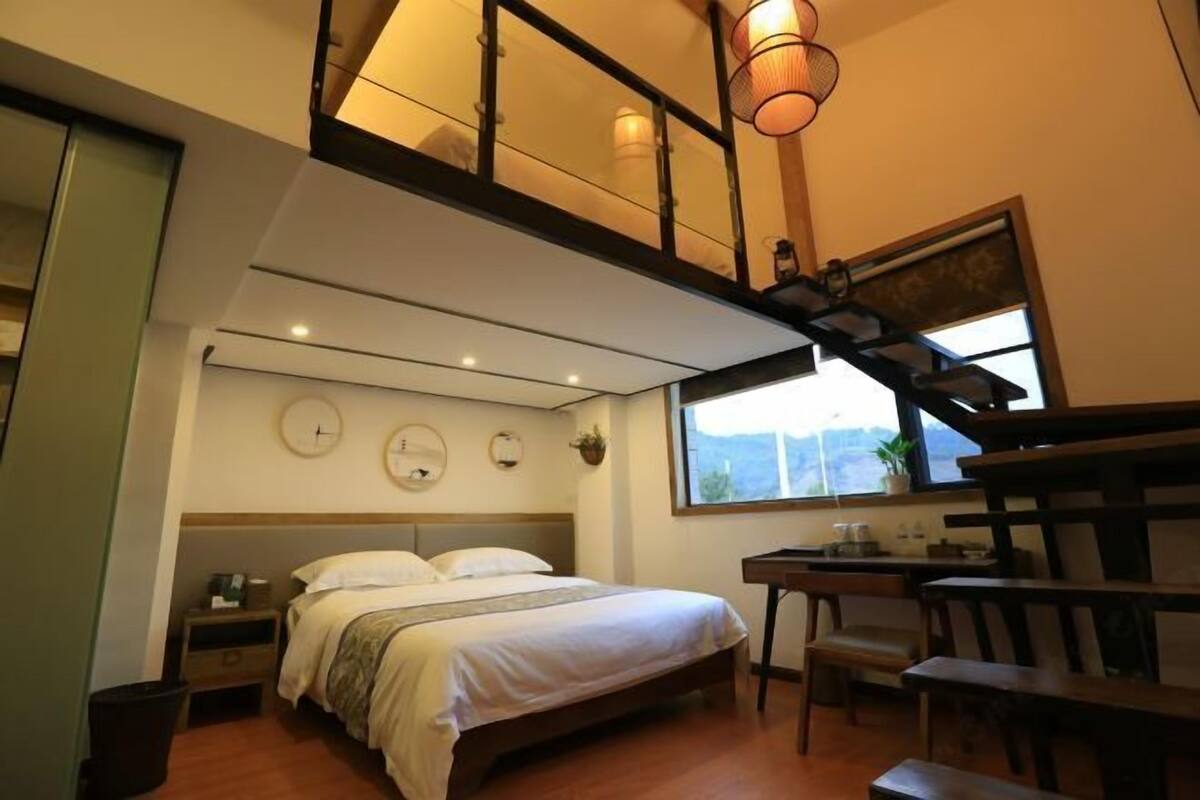 Un dormitorio con cama, mesita de noche, silla, escritorio y ventana con vistas.