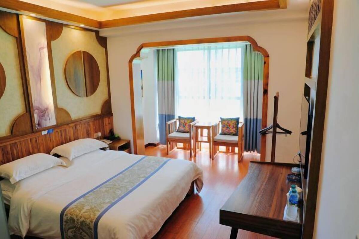 Una habitación de hotel con cama, escritorio, silla y espejo.