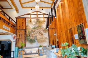 Un interior de madera con mostrador de recepción, zona de estar y un gran mural en la pared.
