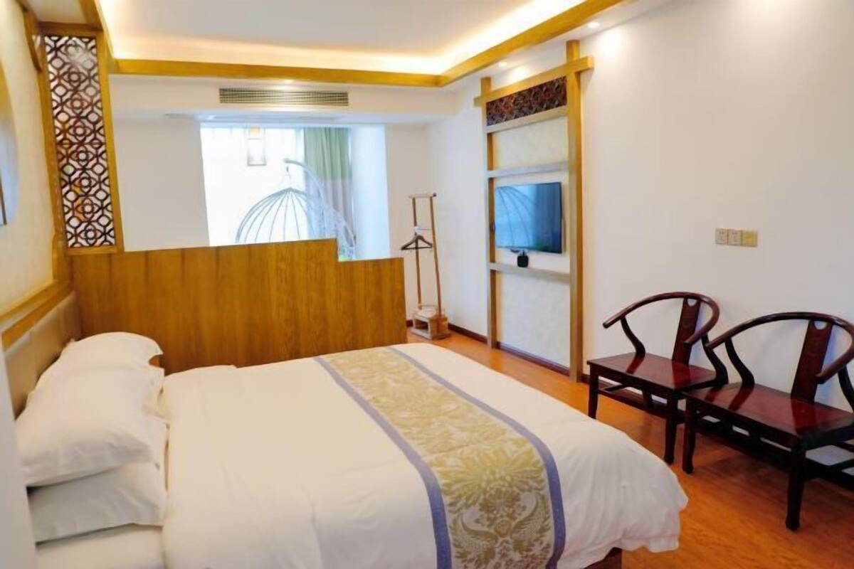 Una habitación de hotel con cama, una silla, ventana con vistas y televisión en la pared.