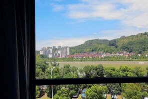 Vista desde una ventana que da a un río, edificios y un paisaje montañoso.