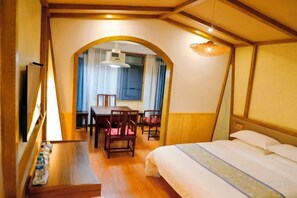 A hotel room with a bed, a desk with chairs, and a window with curtains. - New Bund Fiorist＇s Inn (Zhangjiajie)