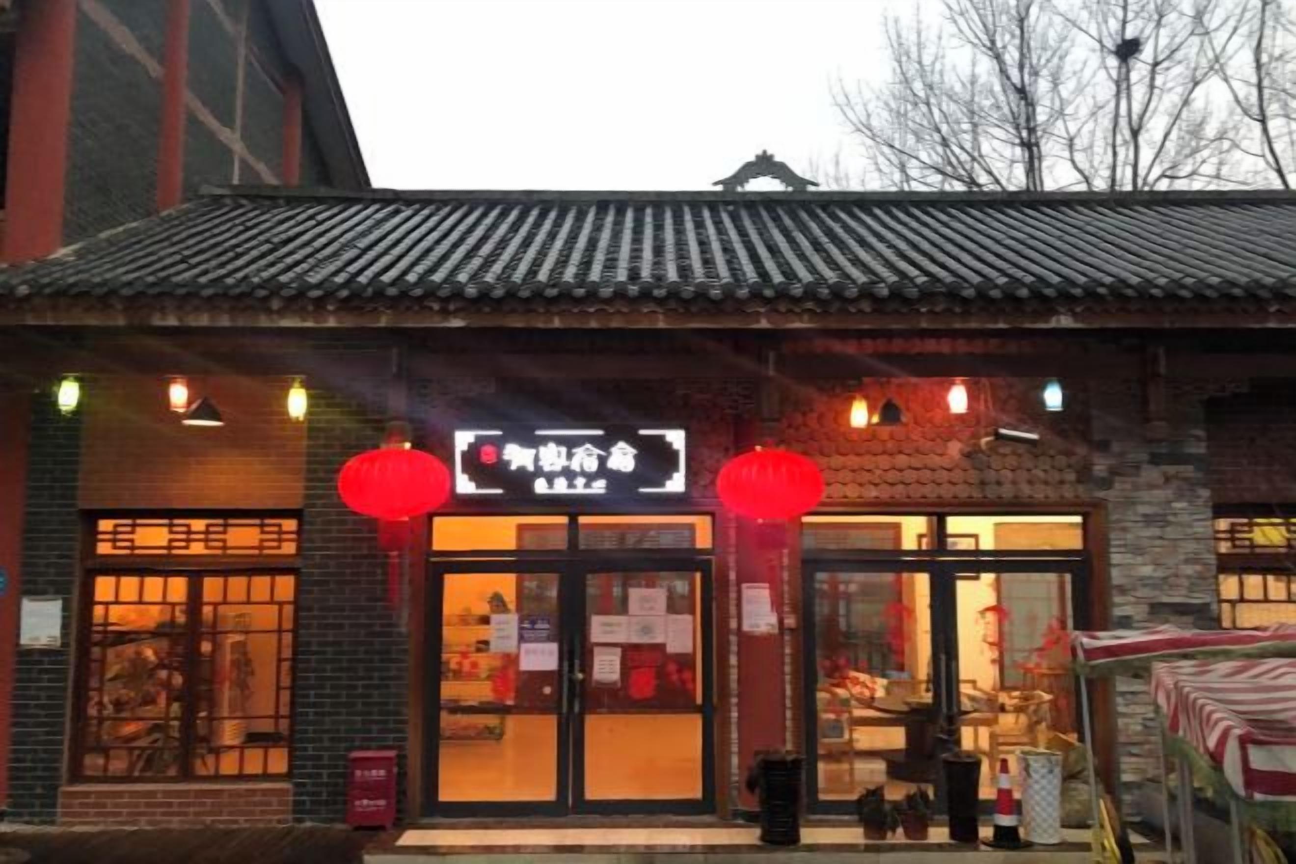 A traditional building with a tiled roof, a signboard, and red lanterns.