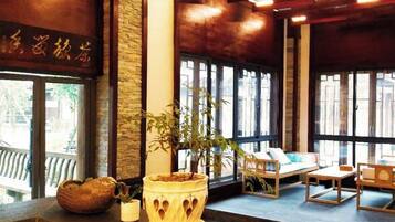 Una habitación con techo de madera, ventanas amplias, un sofá y una mesa con una planta.