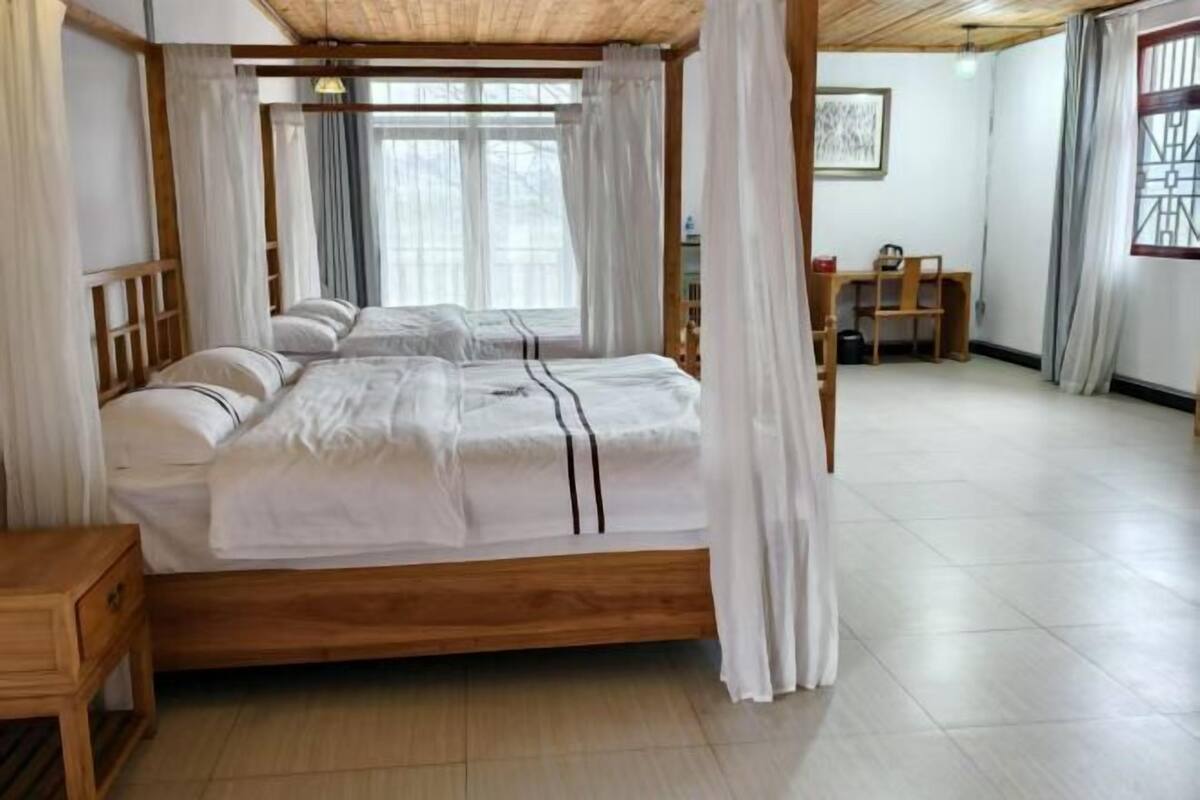 Una cama con dosel con ropa de cama blanca, un cabecero de madera y una mesita de noche pequeña.