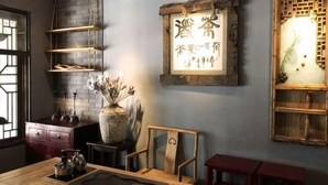 A room with a wooden table, chairs, a vase with dried flowers, shelves, and a wall-mounted sign with Chinese characters. - Youke Susu Hotel (Guiding Yinzhai) (Guiding)