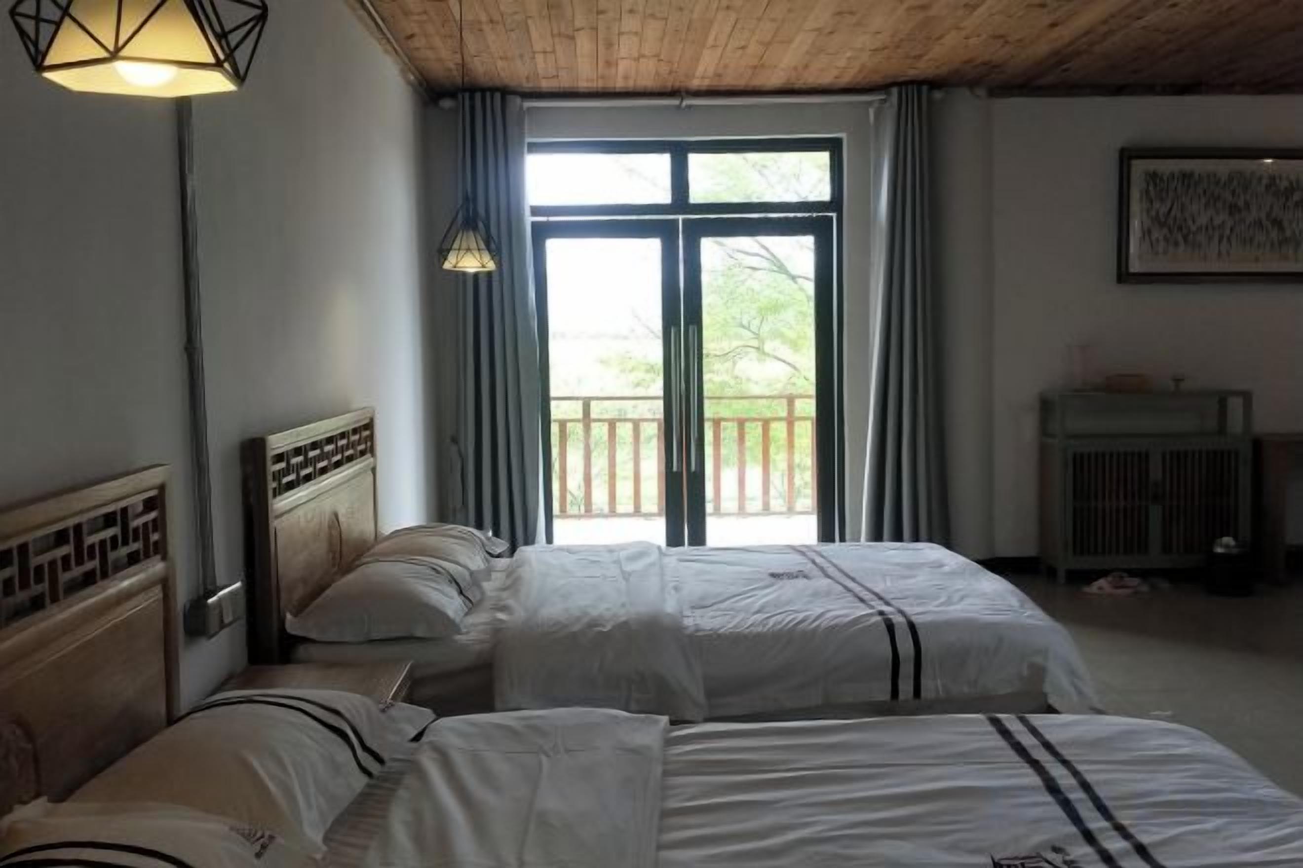 A room with two beds, a balcony, and a window with curtains.