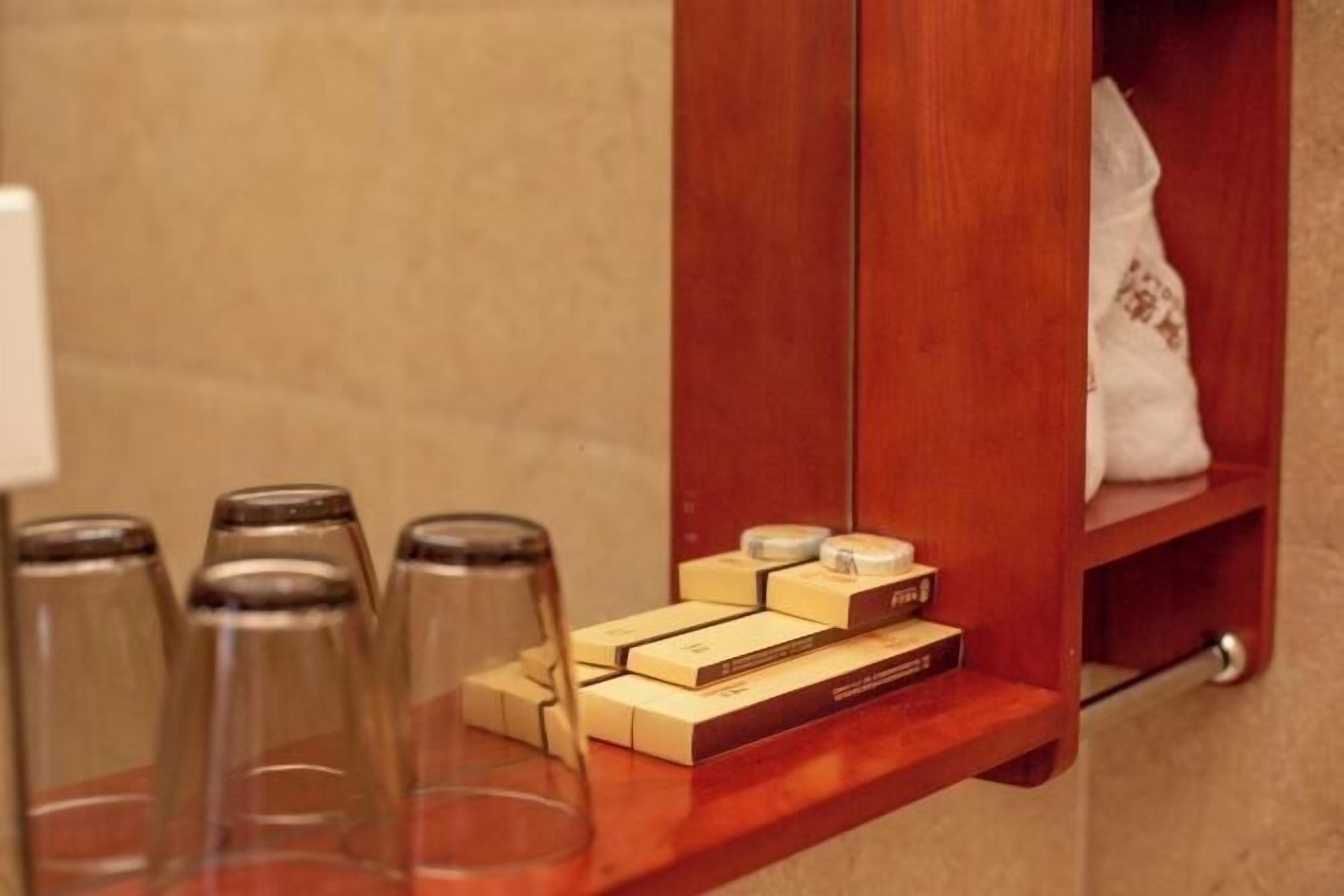 A wooden shelf with toiletries and a white towel in a hotel room.