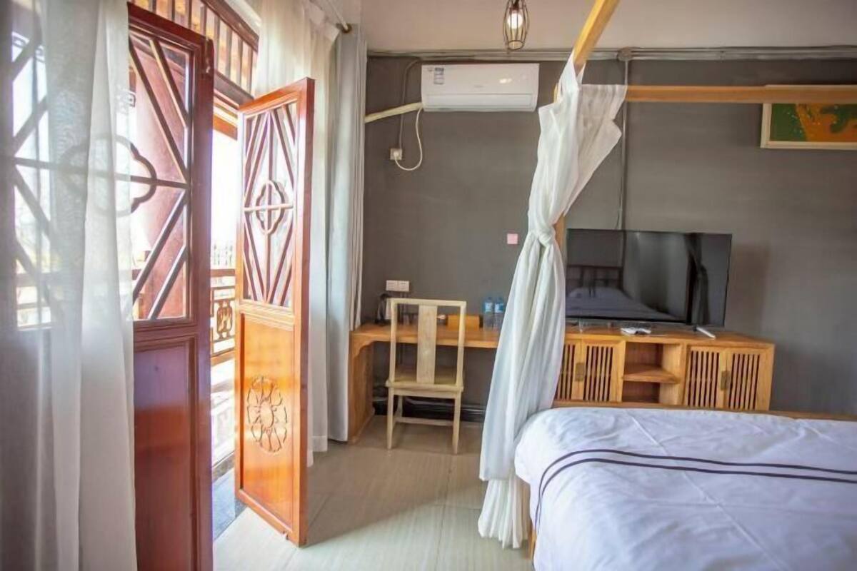 Una habitación de hotel con cama, escritorio, silla, aire acondicionado y televisor.