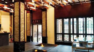 A lobby with stone pillars, a reception desk, and a bench.