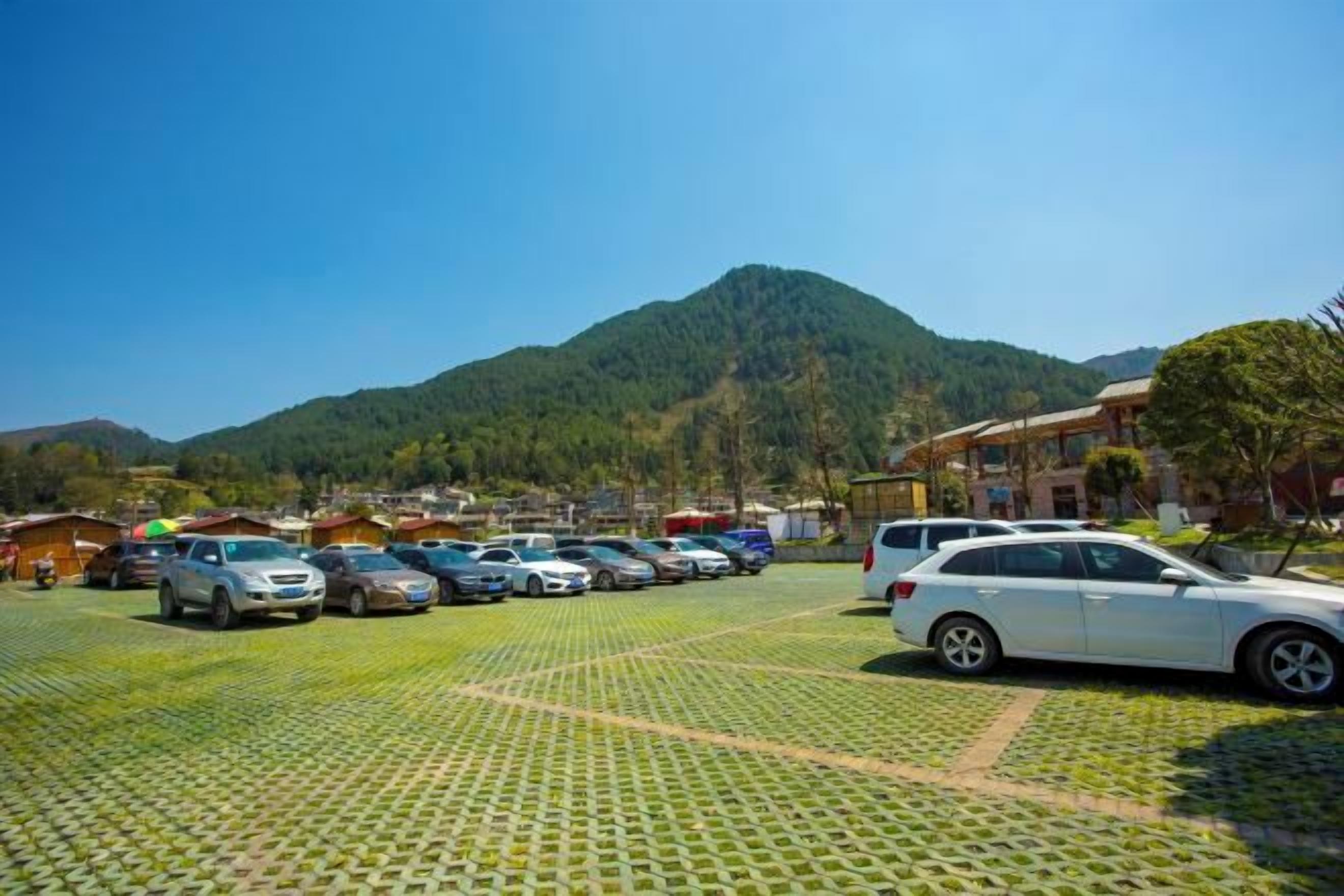 A parking lot with cars and a mountain in the background.