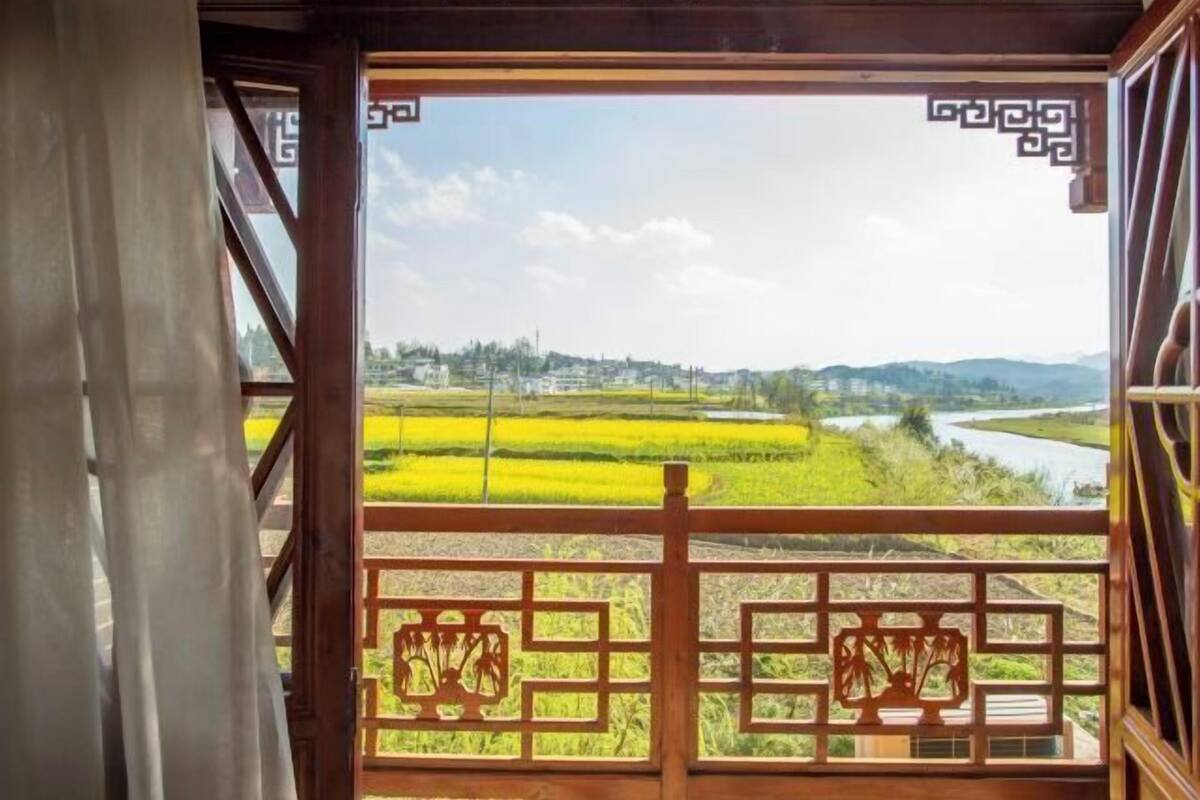 Una habitación con vistas a un río y campos.