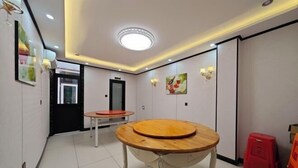 A hotel lobby with a round wooden table, a red stool, and a door leading to another room. - Jingxige Inn (Gouqi Island) (Shengsi)
