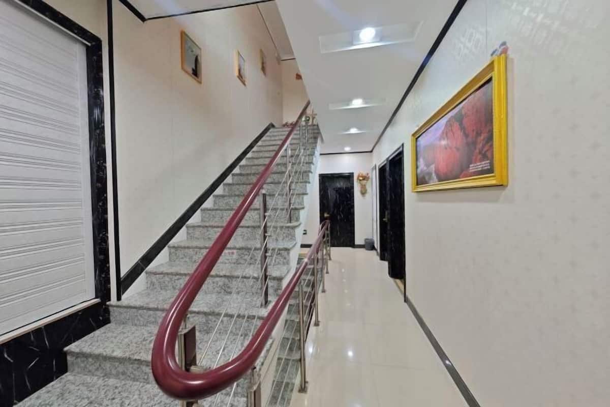 A hotel hallway with a marble staircase, a closed door, and a framed picture on the wall.