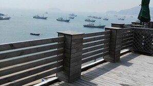 A wooden deck with a railing overlooking a body of water with several boats. - Jingxige Inn (Gouqi Island) (Shengsi)