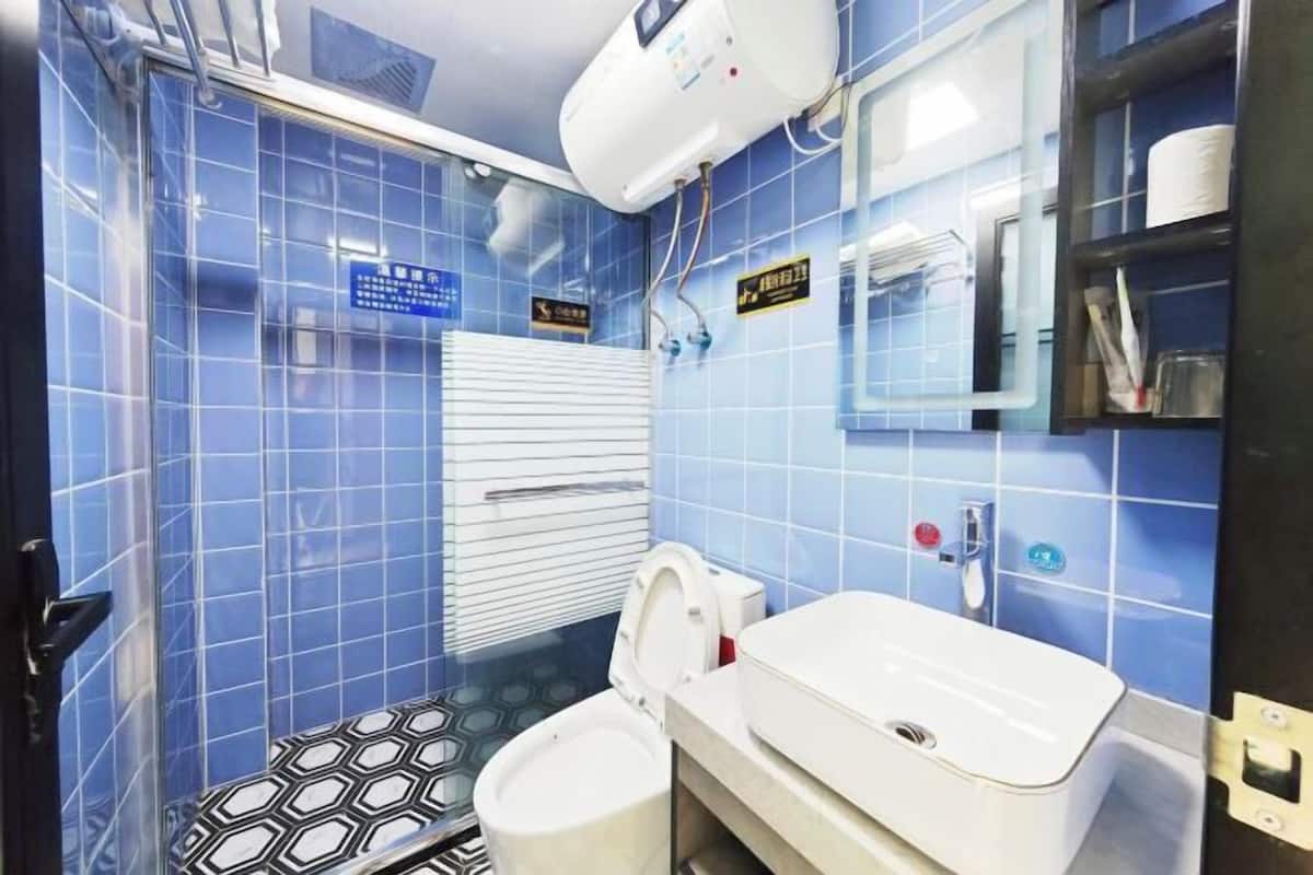 A bathroom with blue tiles, a white toilet, a sink, and a towel rack.