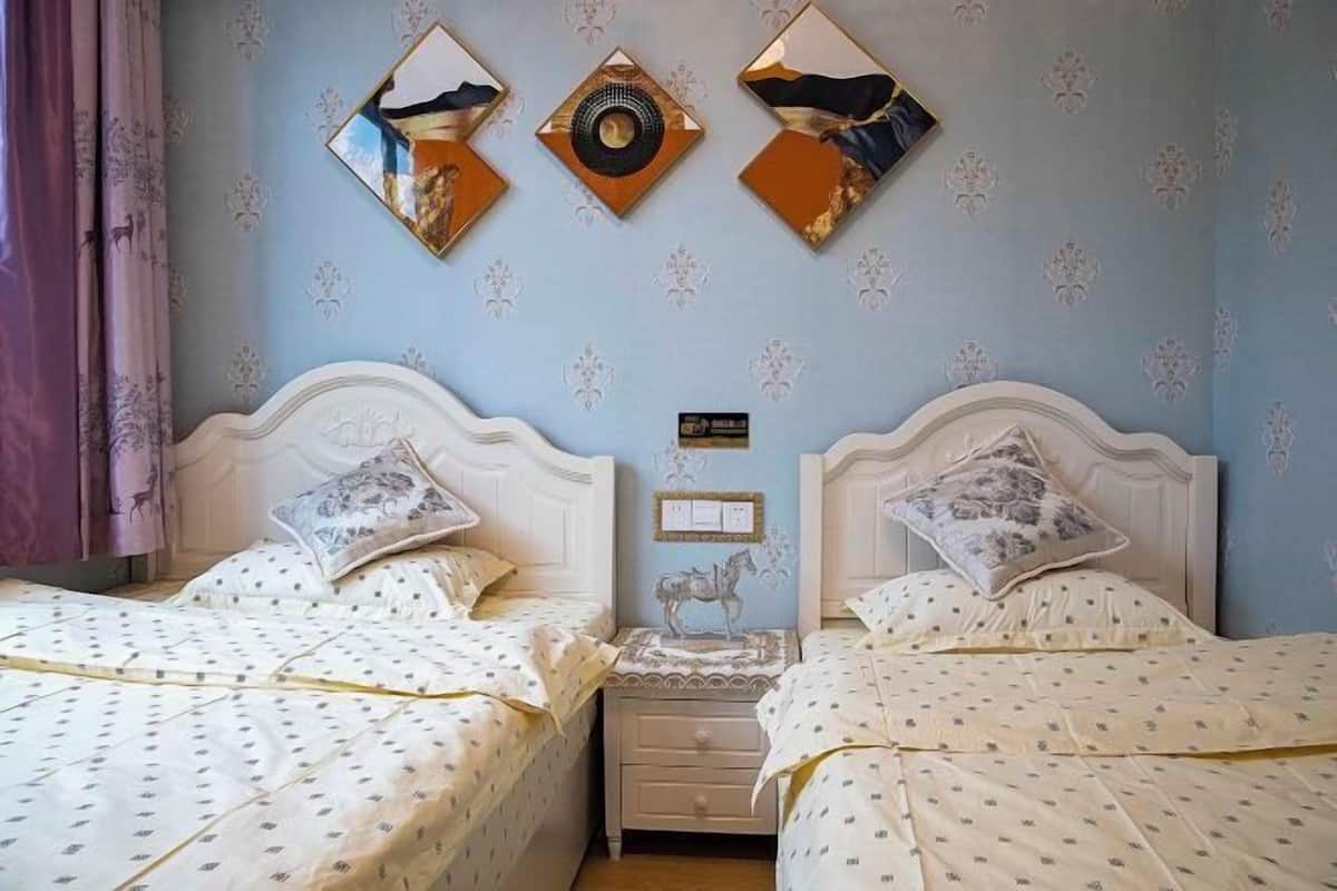 A room with two beds, a nightstand, and decorative wall mirrors.