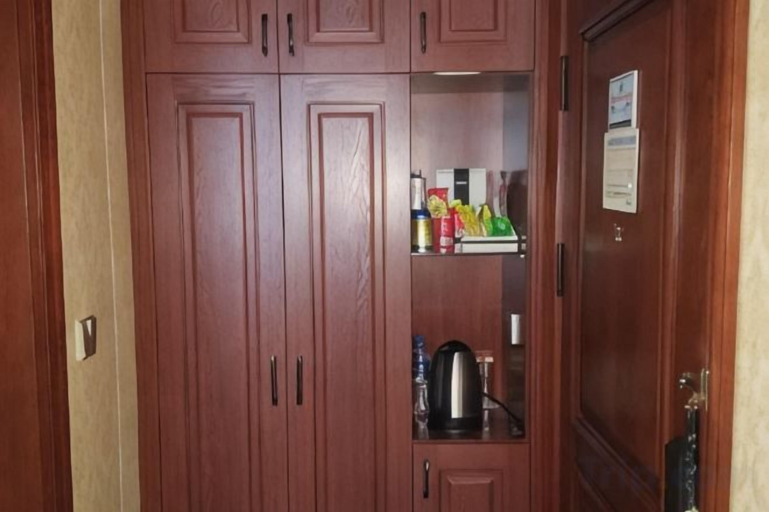 Un armario de madera con espejo, un estante con aperitivos y una tetera.